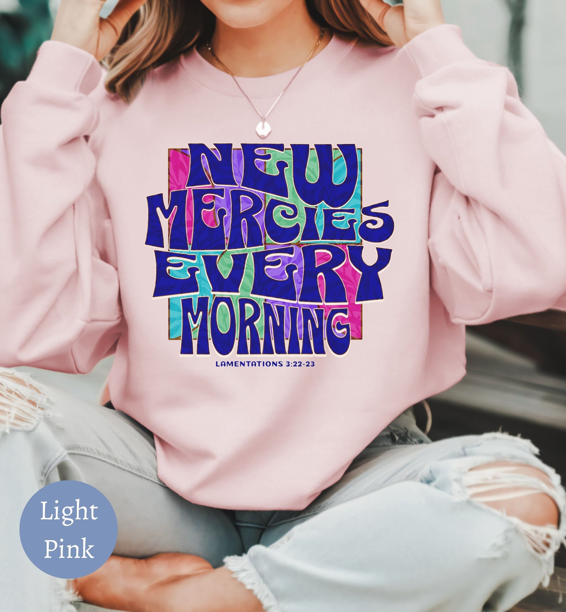 a woman wearing a pink sweatshirt with the words new mercified every morning printed