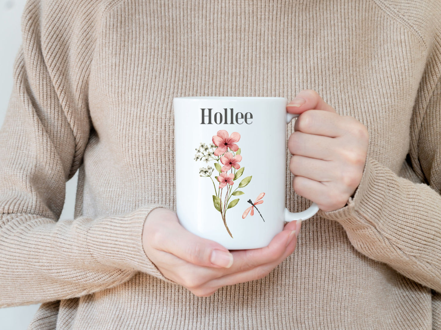 a woman is holding a coffee mug with flowers on it