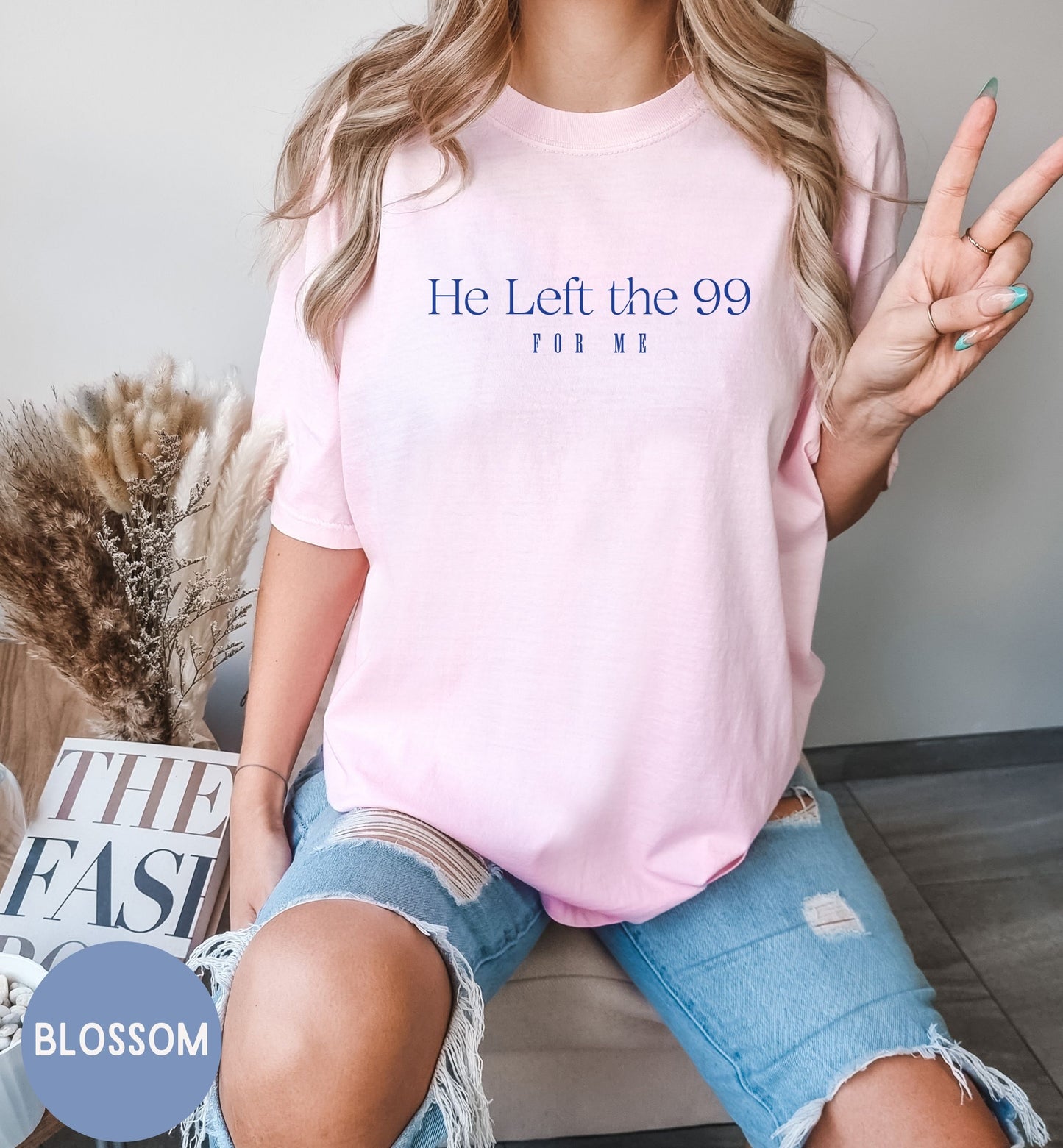 a woman sitting on a couch wearing a pink shirt that says he left the 99