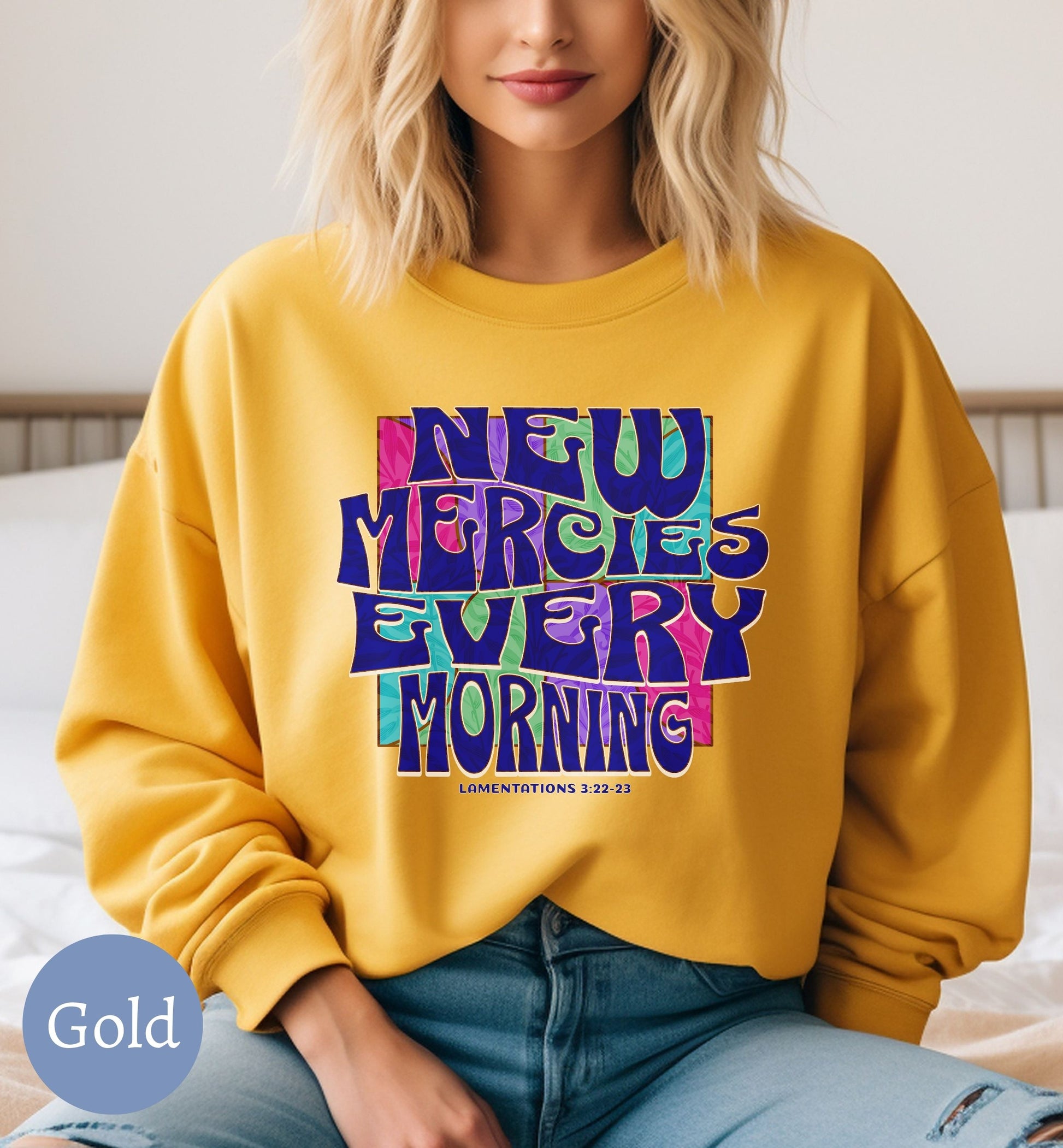 a woman sitting on a bed wearing a yellow sweatshirt