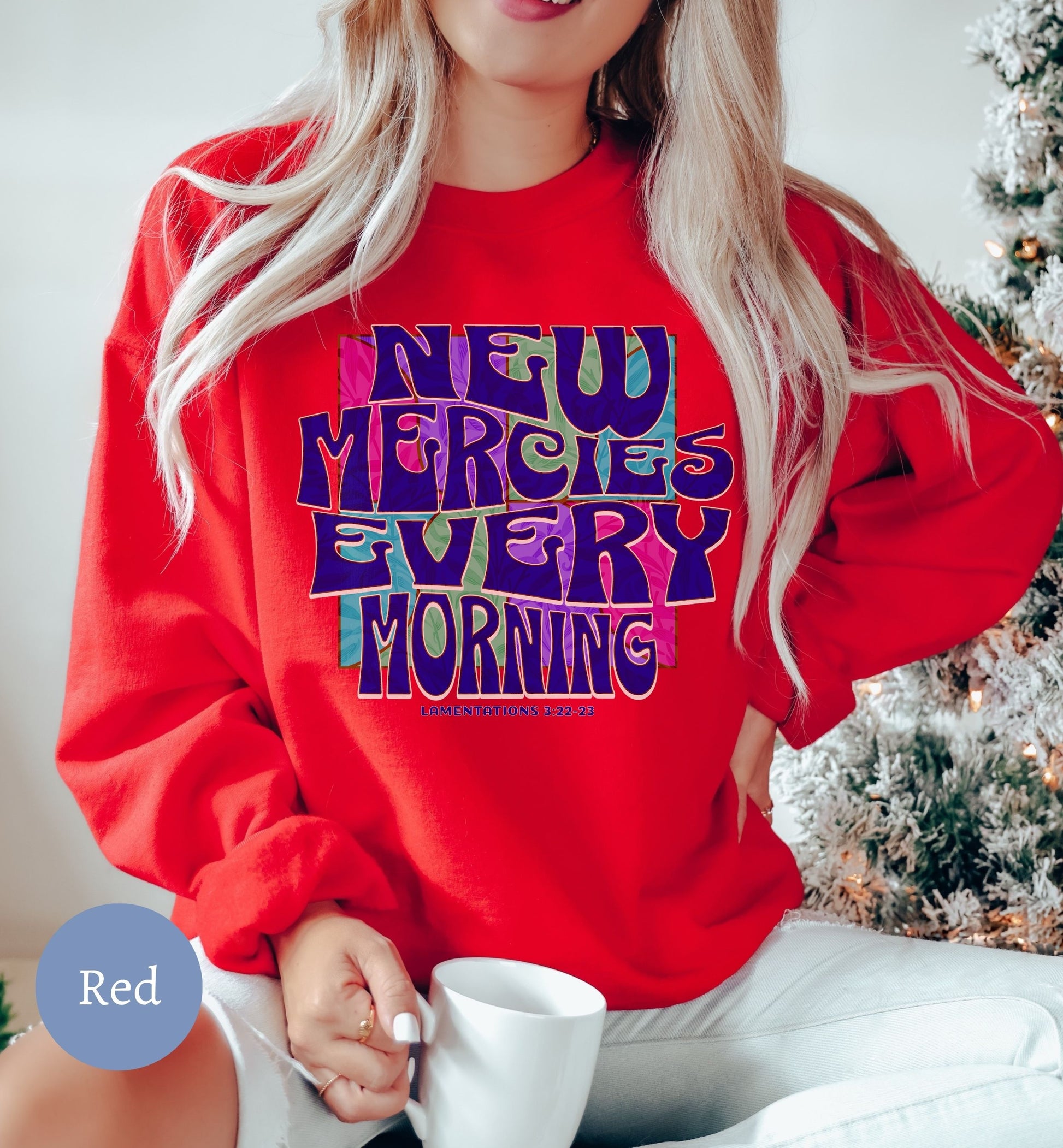 a woman wearing a red sweatshirt with the words new merries every morning on it