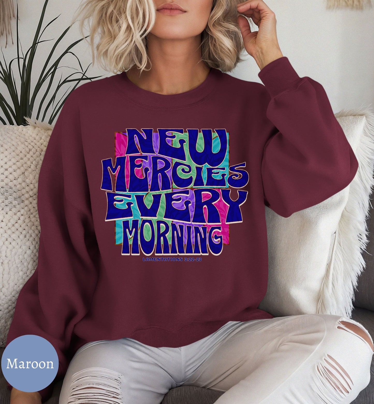 a woman sitting on a couch wearing a sweatshirt that says new mercies every morning